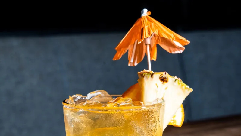 Florida Peach cocktail with Captain Morgan, Tito's, Bacardi, orange juice, pineapple, cranberry, tonic, ginger ale, Sprite and Coke, garnished with a pineapple wedge, orange slice and an orange paper umbrella