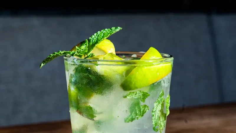 Mojito cocktail — clear citrus drink with fresh mint leaves and lime wedges