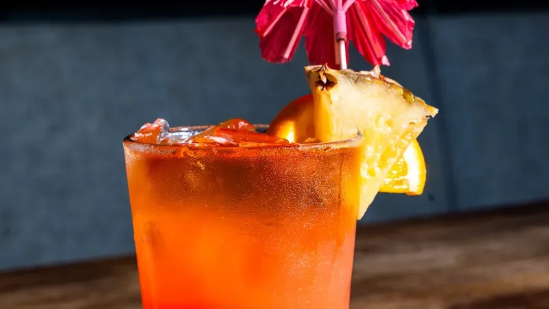 Hush Punch cocktail with Captain Morgan rum, orange juice, pineapple, cranberry and grenadine, garnished with a pineapple wedge, orange slice and a red paper umbrella